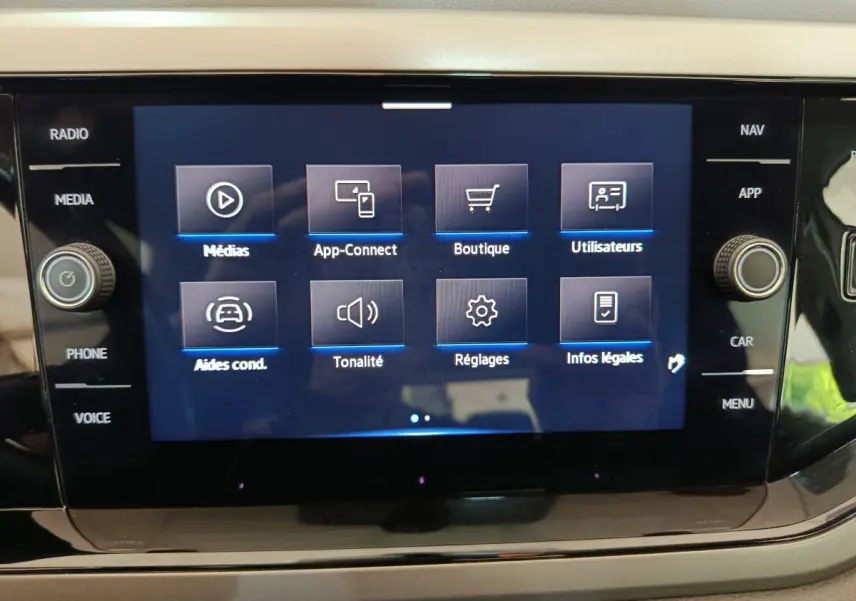 Écran tactile central du tableau de bord de la Volkswagen Polo blanche, affichant le menu multimédia et réglages.
