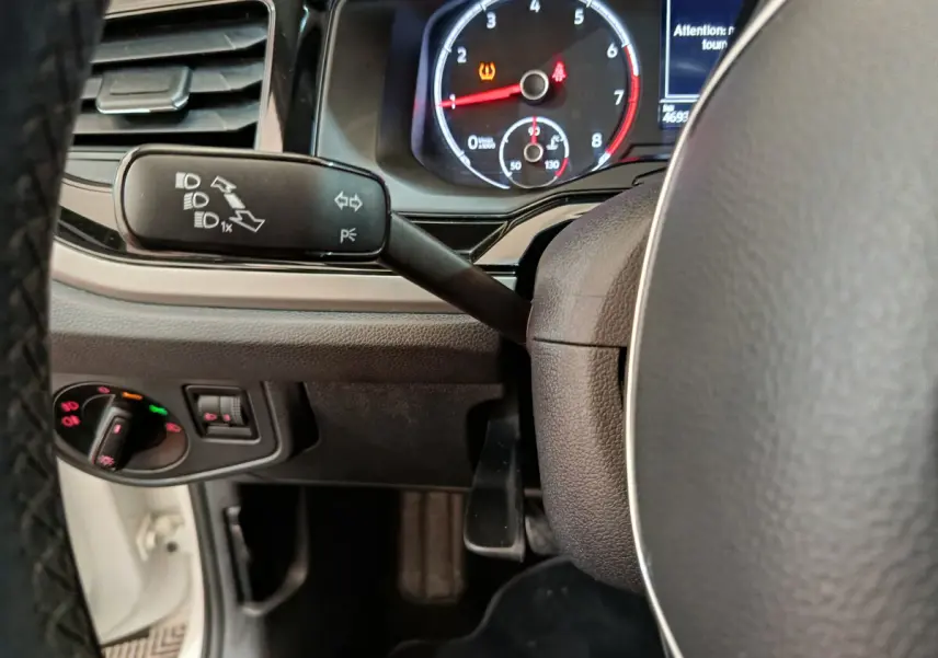 Gros plan sur le tableau de bord et la commande des phares d'une Volkswagen Polo blanche, version 2020, côté conducteur.
