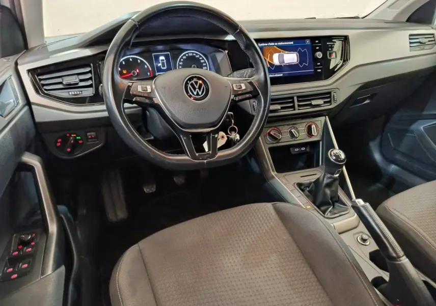 Vue intérieure avant de la Volkswagen Polo blanche 2020, tableau de bord avec écran tactile et volant cuir multifonctions.