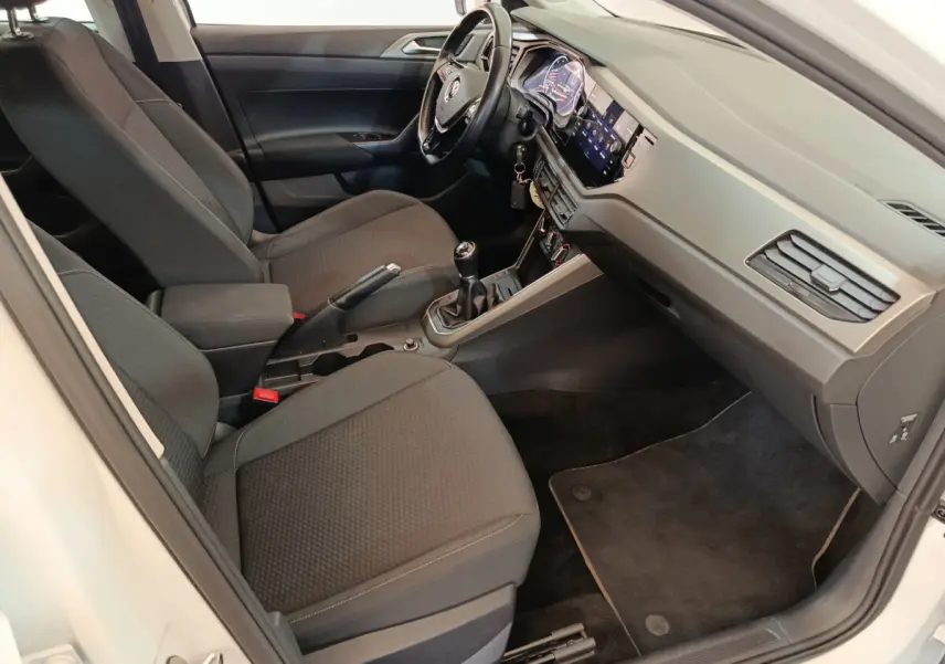 Intérieur avant droit de la Volkswagen Polo blanche 2020, sièges noirs, volant cuir, tableau de bord digital et boîte manuelle.