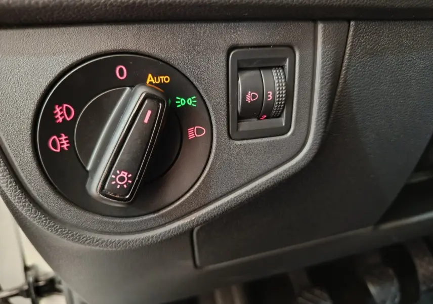 Gros plan sur le bouton de commande des phares et réglage hauteur des feux dans une Volkswagen Polo blanche 2020.