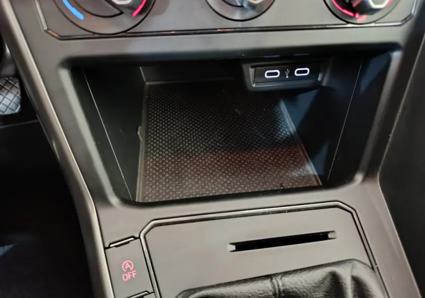 Gros plan sur la console centrale noire de la Volkswagen Polo blanche, montrant la zone de rangement et ports USB.