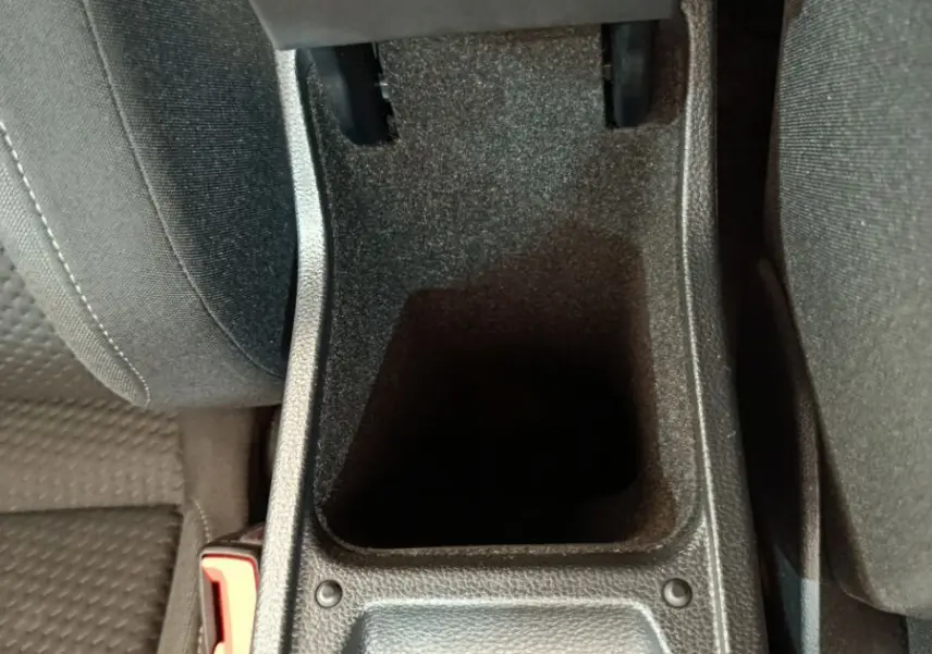 Vue plongeante sur le rangement central noir entre les sièges avant d'une Volkswagen Polo blanche 2020.