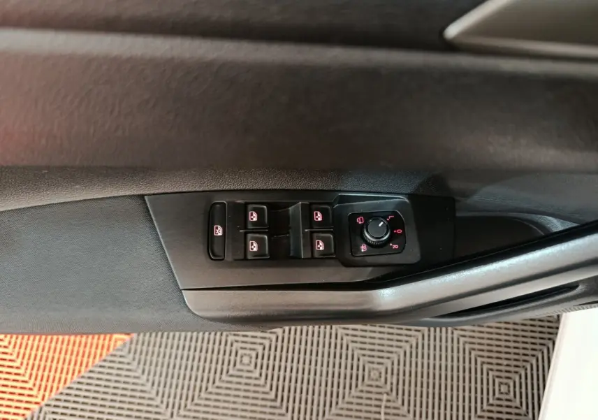 Gros plan sur les commandes de lève-vitres et rétroviseurs côté conducteur d'une Volkswagen Polo blanche 2020.