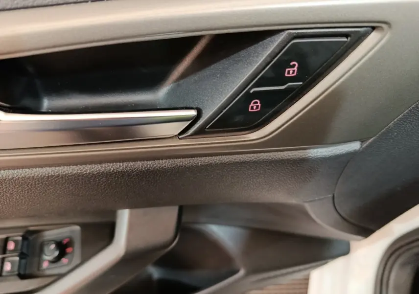 Détail de la poignée intérieure et des boutons de verrouillage de porte côté conducteur d'une Volkswagen Polo blanche 2020.