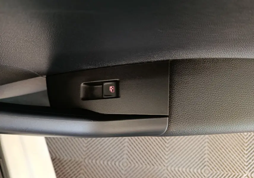 Bouton de verrouillage centralisé sur la porte intérieure noire d'une Volkswagen Polo blanche vue côté gauche.