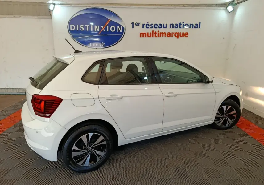 Volkswagen Polo blanche vue de profil côté gauche dans un showroom avec jantes noires et rouges arrière visibles.