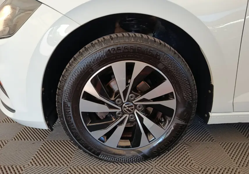 Gros plan sur la roue avant gauche d'une Volkswagen Polo blanche, jante alliage bicolore au design moderne.