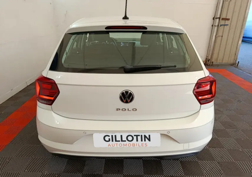 Vue arrière d'une Volkswagen Polo blanche 2020 stationnée en intérieur avec logo VW visible et feux rouges.