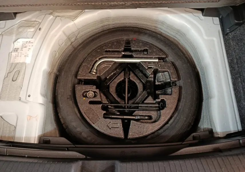 Vue plongeante sur la roue de secours et les outils de bord dans le coffre d'une Volkswagen Polo blanche 2020.