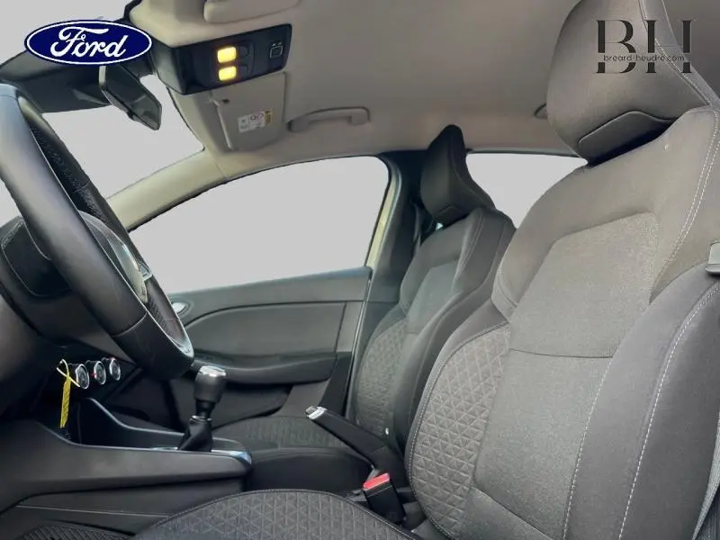 Vue intérieure côté gauche montrant les sièges avant en tissu noir avec motifs surpiqués et levier de vitesse manuel