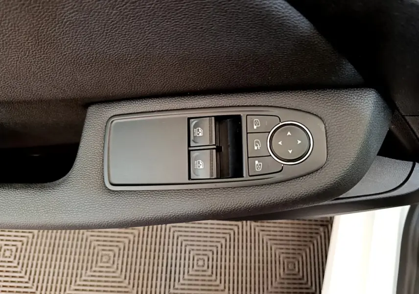 Commande des vitres et rétroviseurs sur la porte côté conducteur d'une Renault Clio Business Blue dCi 85 blanche, vue intérieure rapprochée.
