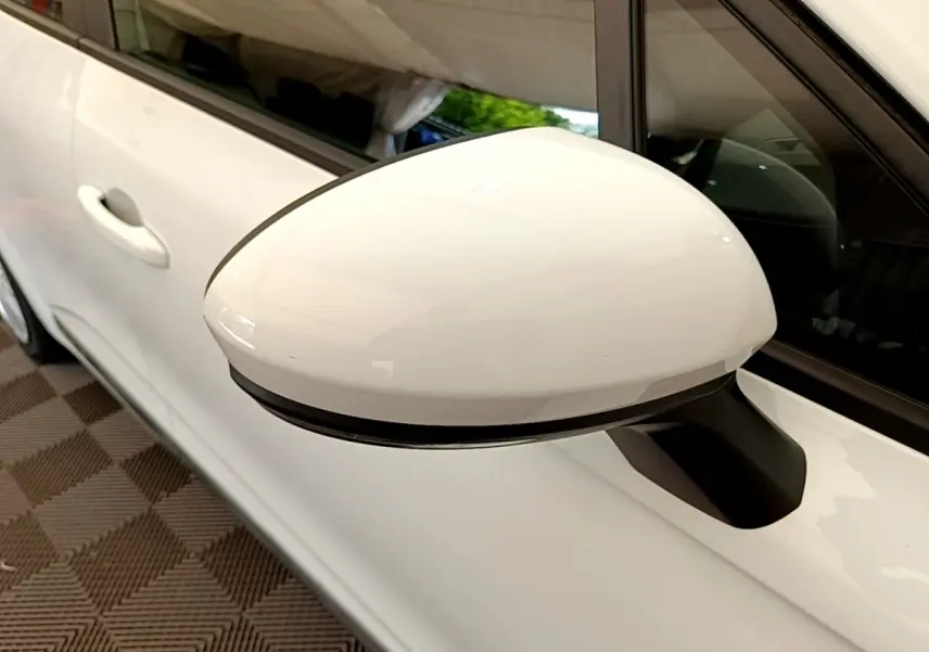 Gros plan sur le rétroviseur droit blanc d’une Renault Clio Business Blue dCi 85 de 2020, avec porte et vitre arrière visibles.