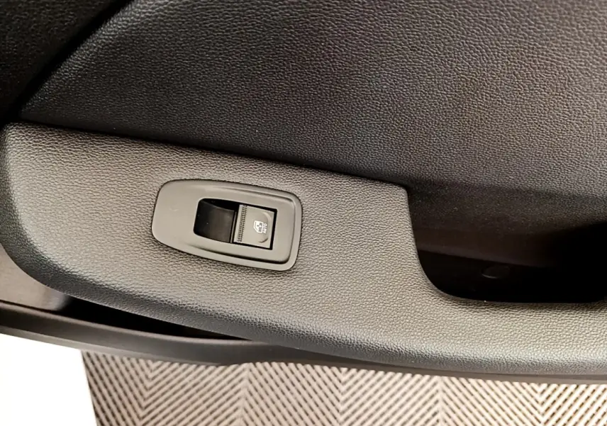 Gros plan sur le bouton de commande de la vitre électrique côté porte intérieure, finition noire texturée.