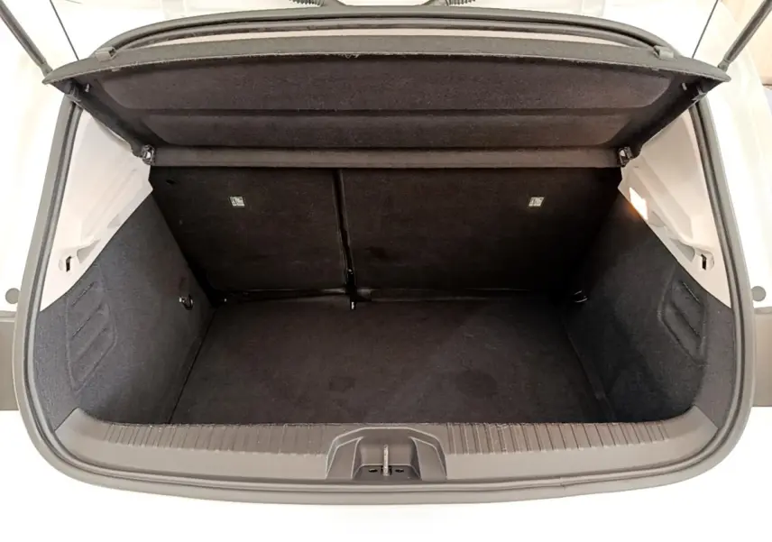 Vue plongeante sur le coffre ouvert d’une Renault Clio Business Blue dCi 85 blanc, montrant l’espace de rangement noir.