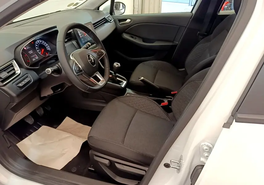 Vue intérieure côté conducteur de la Renault Clio Business Blue dCi blanche, montrant le volant cuir et la console centrale.
