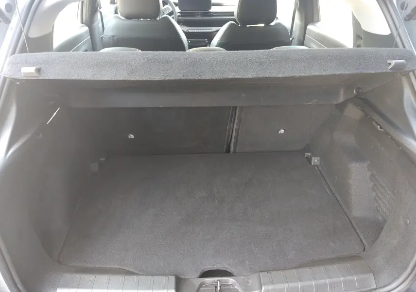 Vue intérieure du coffre spacieux du Jeep Avenger eHYBRID 110ch gris, avec banquette arrière et tablette cache-bagages visibles.