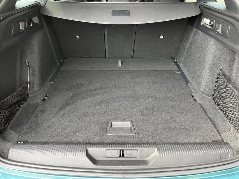 Coffre ouvert vu de l'arrière d'une Peugeot 308 SW Bleu Avatar, espace de chargement plat et tapis noir.