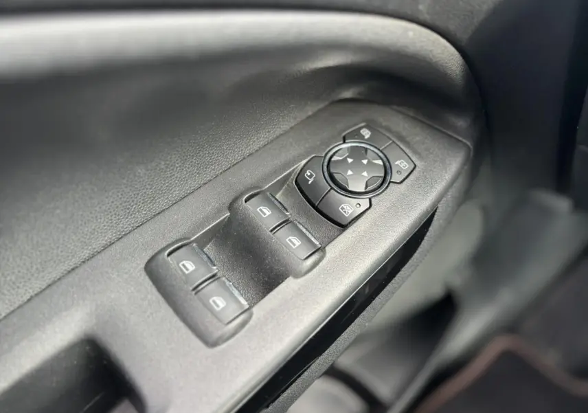 Gros plan sur les commandes des vitres et rétroviseurs côté conducteur d'un Ford EcoSport 2019 noir.