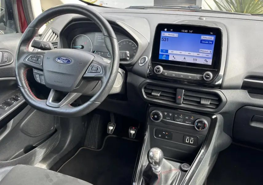 Vue intérieure côté conducteur du Ford EcoSport rouge 2019, volant cuir ST-Line et écran tactile GPS visible.