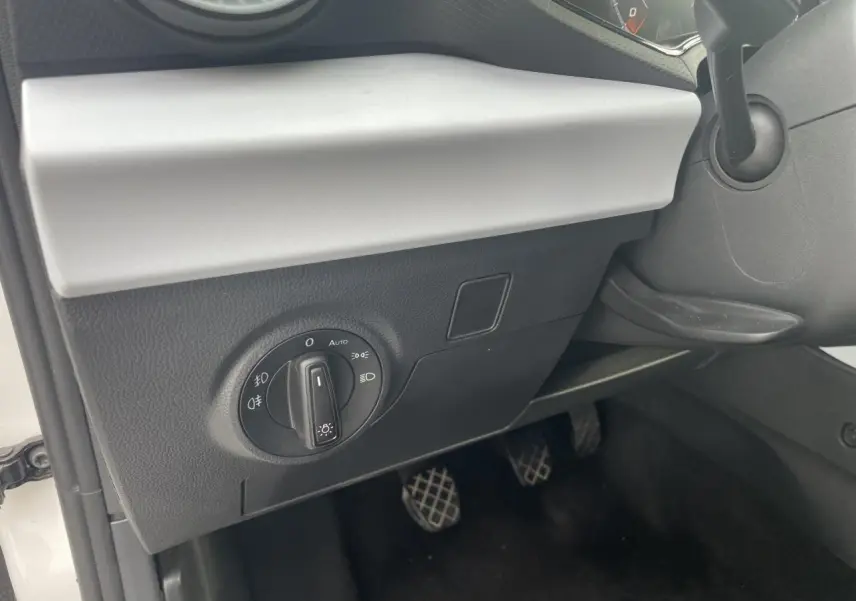 Détail du tableau de bord côté gauche de la SEAT Ibiza blanche 2025 avec commande des feux et pédalier manuel visible.