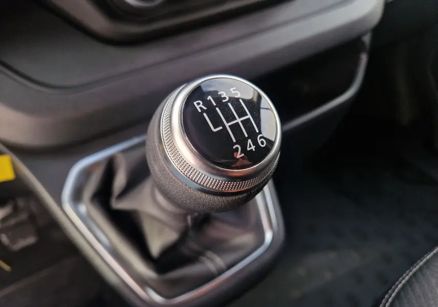 Gros plan sur le levier de vitesses manuel noir du Nissan Primastar 2025 avec marquage des rapports blancs.