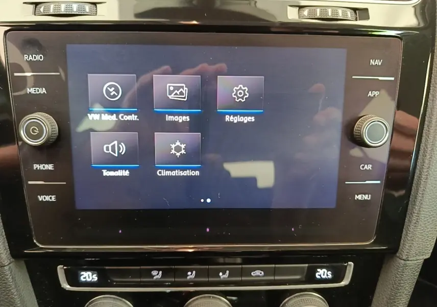 Gros plan sur l'écran tactile central et les commandes de climatisation d'une Volkswagen Golf bleue de 2020.