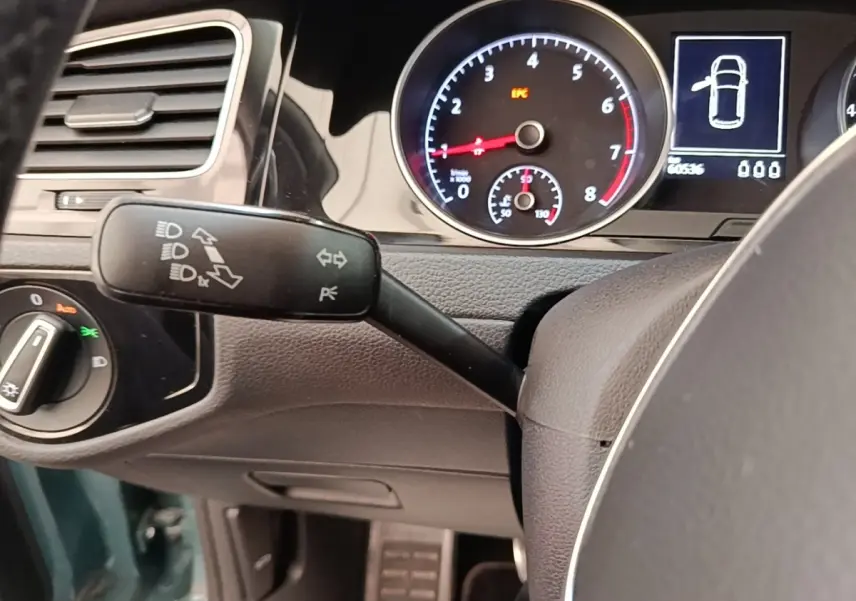 Gros plan sur le tableau de bord et commodo gauche de la Volkswagen Golf bleue, avec compte-tours et affichage digital.