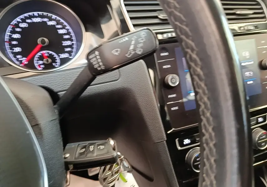 Gros plan sur le volant cuir et tableau de bord noir de la Volkswagen Golf 2020 avec écran tactile et commandes multifonctions.