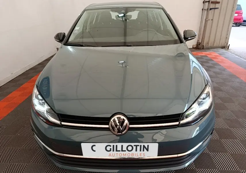 Vue avant d'une Volkswagen Golf bleu 2020 avec phares LED allumés dans un garage.
