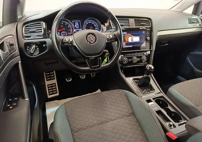 Vue intérieure avant de la Volkswagen Golf 1.0 TSI bleue, volant cuir multifonctions et boîte manuelle visible.