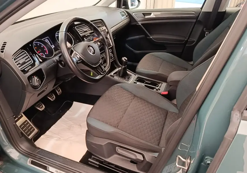 Vue intérieure côté conducteur d'une Volkswagen Golf bleu 2020, volant cuir multifonctions et sièges tissu gris.