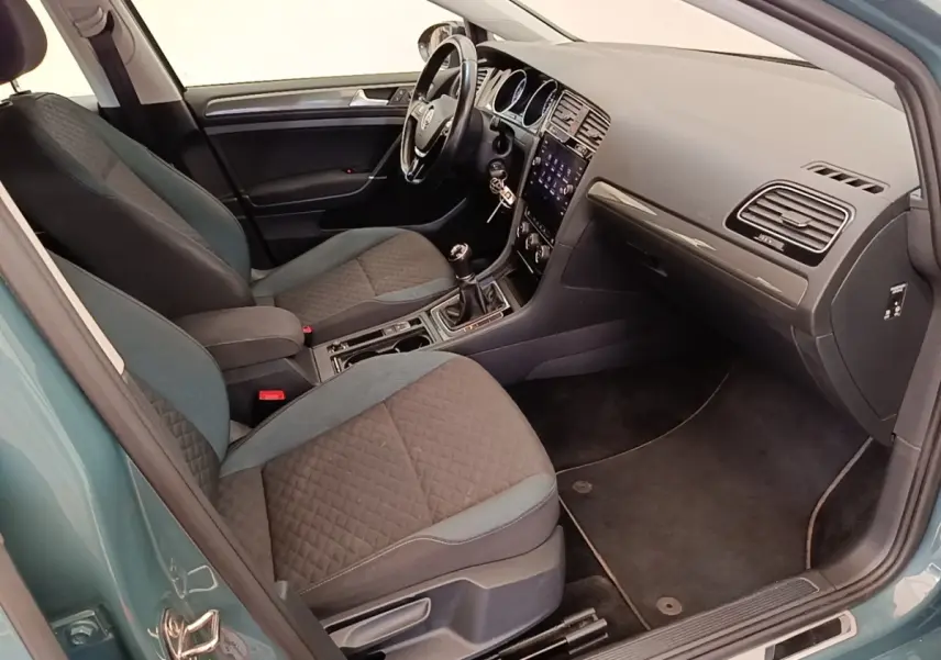 Vue intérieure côté conducteur de la Volkswagen Golf 1.0 TSI bleu, avec volant cuir multifonctions et tableau de bord tactile.