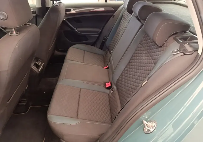 Vue intérieure côté droit sur la banquette arrière gris foncé à motifs losanges d’une Volkswagen Golf bleue.