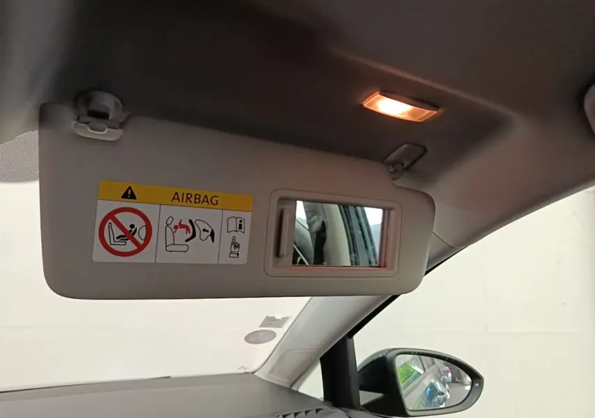 Vue intérieure du pare-soleil côté conducteur avec miroir intégré et avertissement airbag sur une Volkswagen Golf bleue.