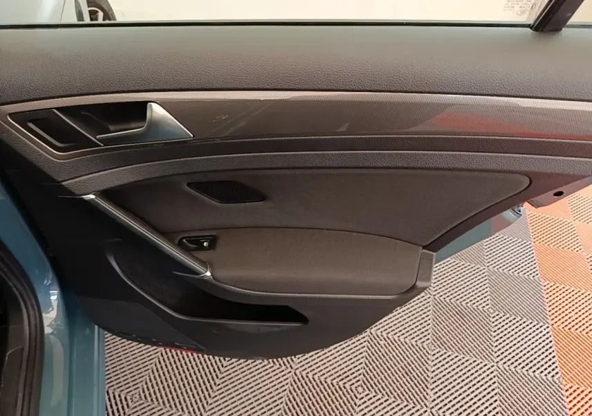 Vue intérieure côté gauche de la porte avant d’une Volkswagen Golf bleu 2020 avec garniture noire et poignée argentée.