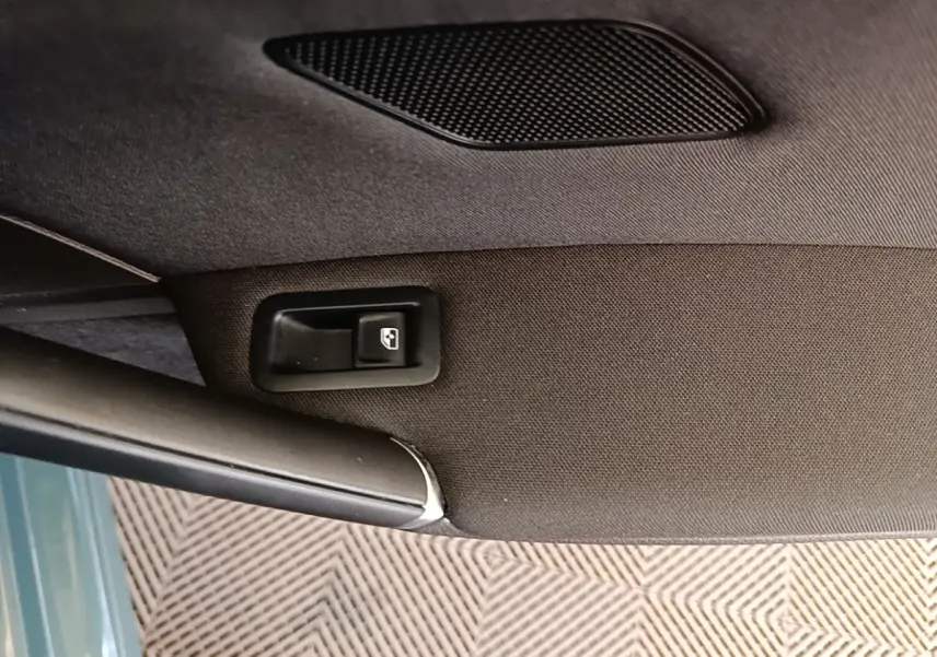 Détail de la commande de lève-vitre sur la porte intérieure d’une Volkswagen Golf bleue.