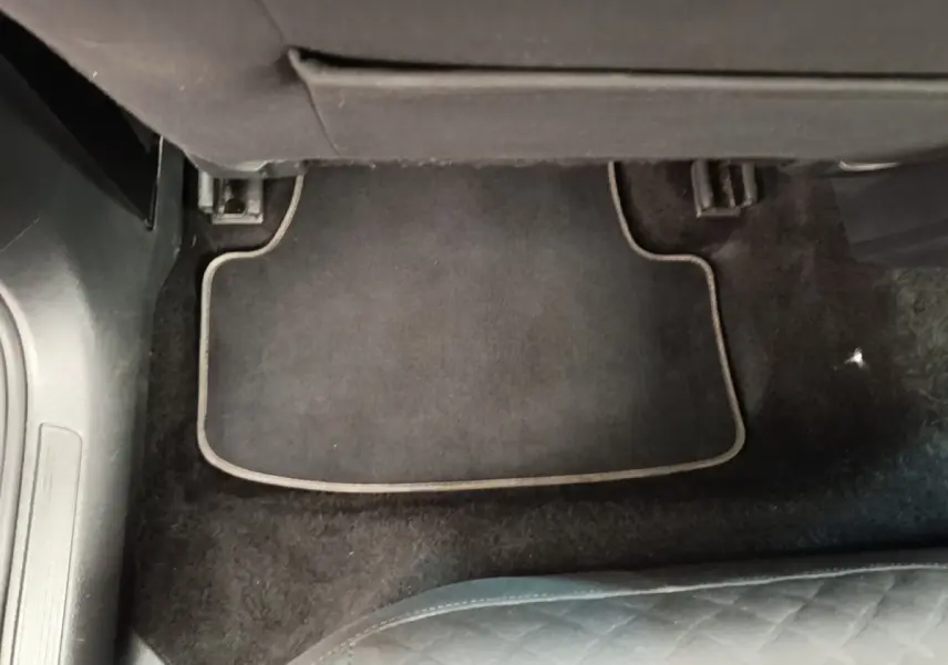 Vue du tapis de sol noir côté passager arrière d'une Volkswagen Golf bleue 2020, intérieur sobre et propre.
