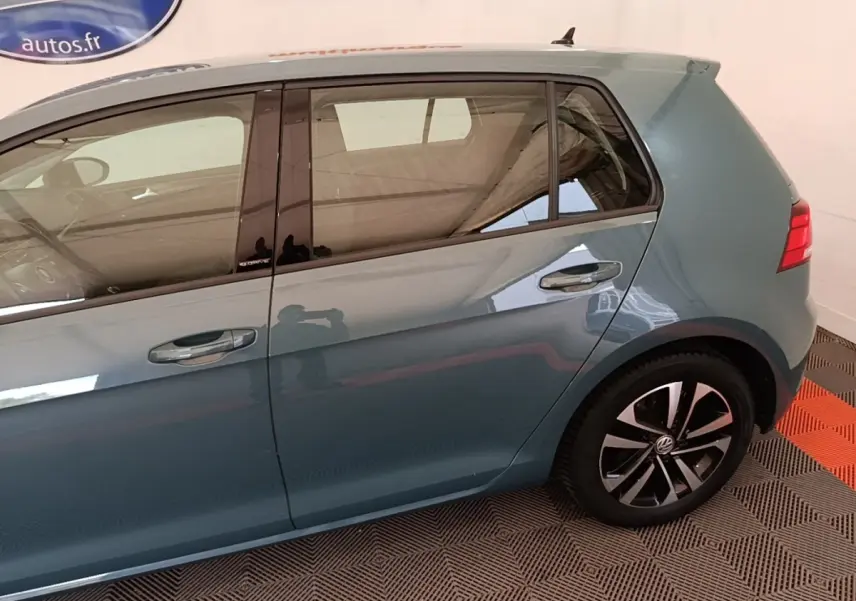 Vue côté droit arrière d'une Volkswagen Golf bleu métallisé avec jantes alliage et vitres teintées.