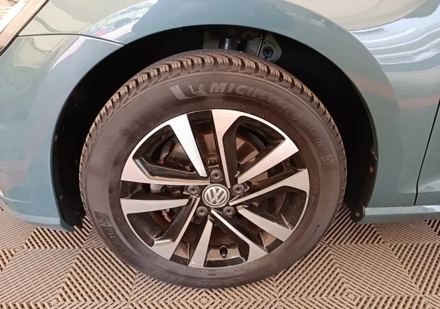 Gros plan sur la roue avant droite d’une Volkswagen Golf bleu 2020 avec jante alliage bicolore et pneu Michelin.
