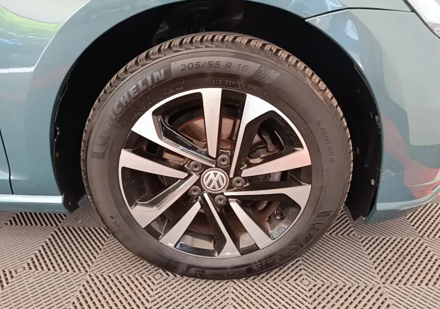 Gros plan sur la roue avant droite d'une Volkswagen Golf bleu, avec jante alliage bicolore et pneu Michelin.