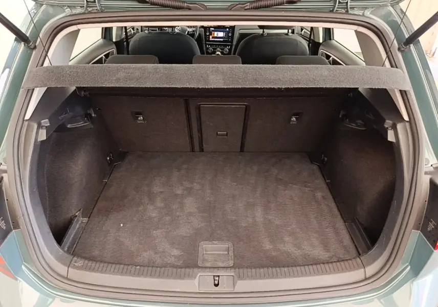 Vue arrière du coffre ouvert d’une Volkswagen Golf bleu 2020, intérieur noir avec tablette de séparation visible.