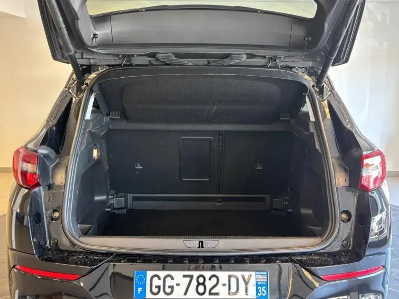 Coffre ouvert vu de l'arrière d'un Opel Grandland noir diamant métallisé, montrant l'espace de chargement vide.