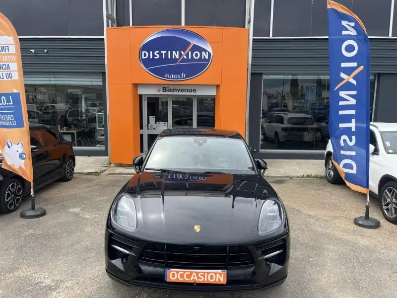 Vue avant d'un Porsche Macan noir avec plaque "OCCASION" devant une concession Distinxion.