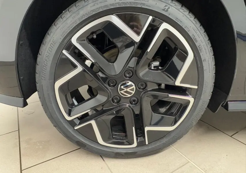 Gros plan sur la roue avant droite d'une Volkswagen Golf 2.0 TDI noire avec jante alliage noir et argent.