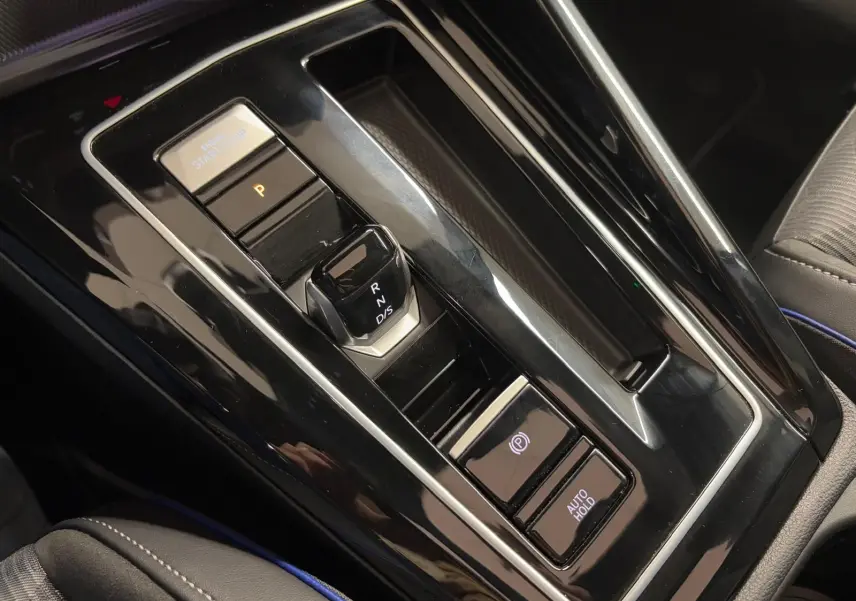 Gros plan sur la console centrale noire brillante de la Volkswagen Golf 2.0 TDI 150 DSG7 R-Line avec levier de vitesses électronique.