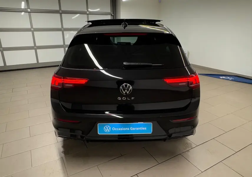 Vue arrière d'une Volkswagen Golf 2.0 TDI noire Grenadille avec feux allumés dans un garage fermé.