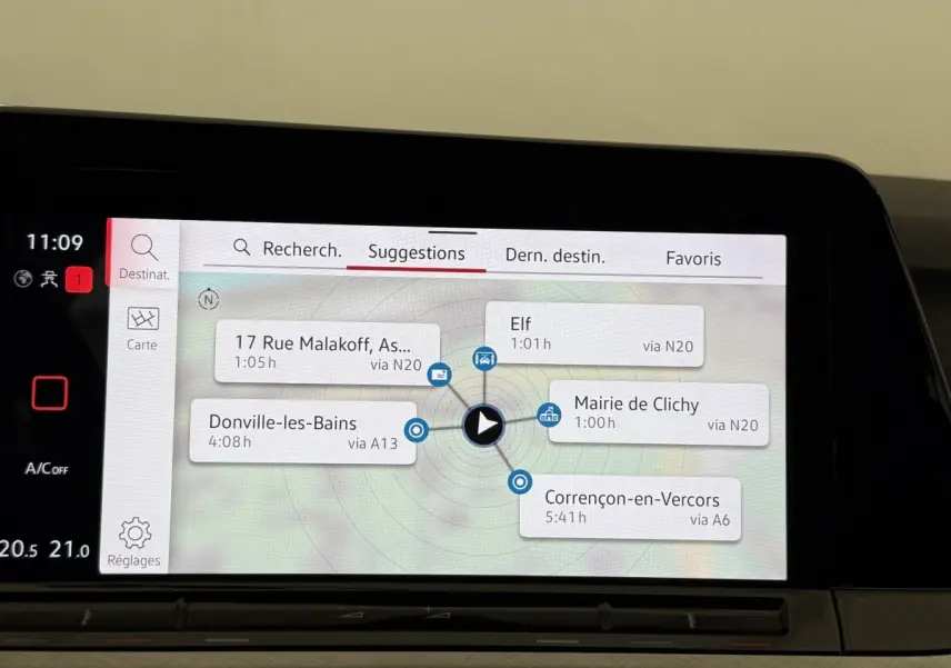 Écran tactile central du tableau de bord de la Volkswagen Golf bleu, affichant le menu de navigation avec suggestions d’itinéraires.