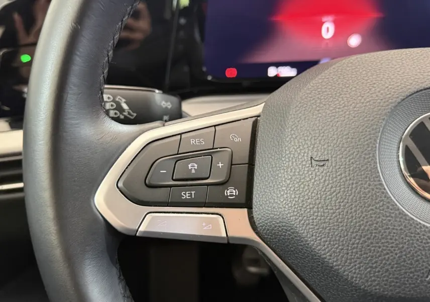 Gros plan sur le volant cuir de la Volkswagen Golf bleu 2021, avec commandes du régulateur adaptatif visibles.