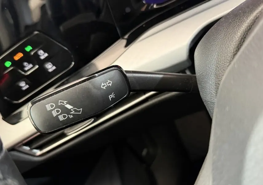 Gros plan sur la commande de clignotants noire dans l’habitacle de la Volkswagen Golf bleu, avec tableau de bord en arrière-plan.